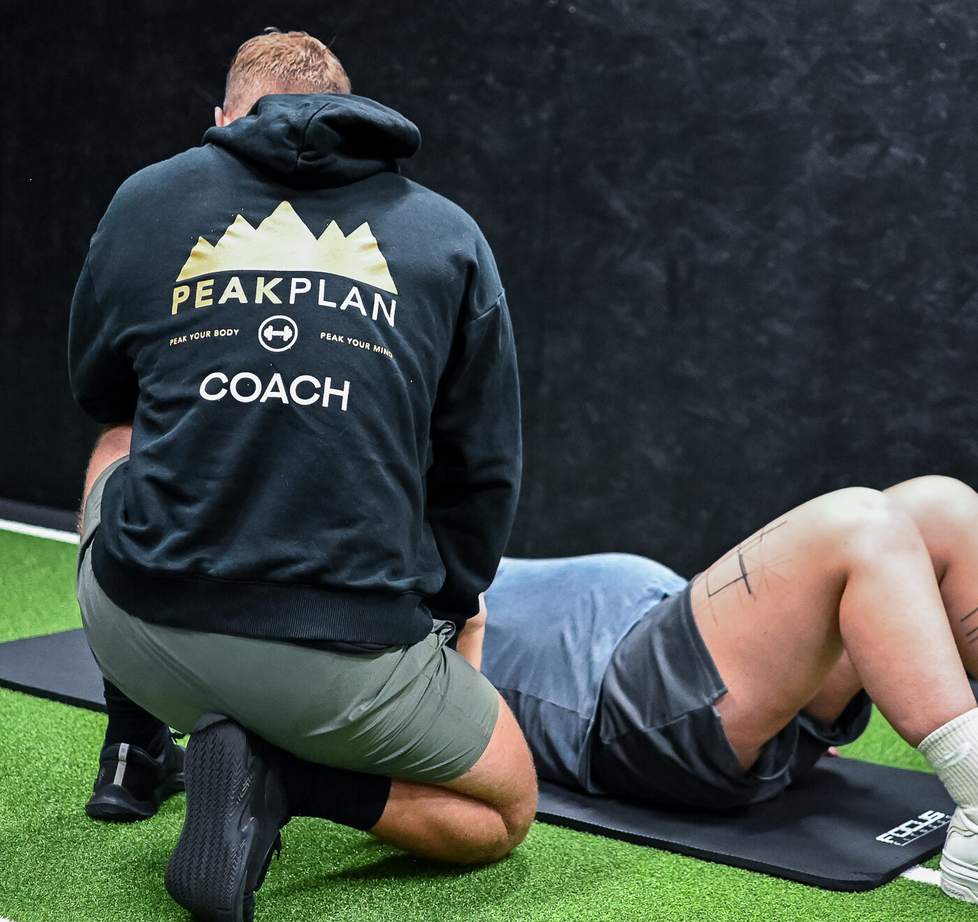 Een coach van Peak Plan begeleidt een oefening in de studio